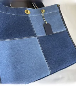 Close-up of patchwork denim tote bag with gold turn-lock closure and white contrast stitching