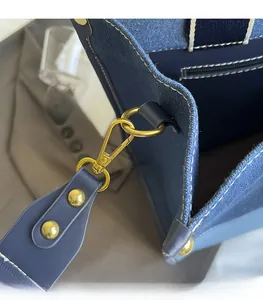 Detail of blue denim tote bag featuring premium gold metal hardware and fine stitching