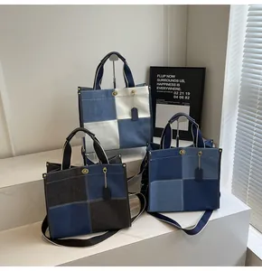 Detail of denim patchwork tote bags with metal clasp and leather strap on marble