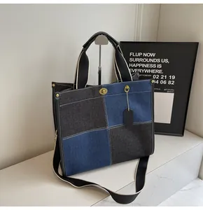 Macro detail of color-block denim tote bag with gold rotary buckle and contrast stitching