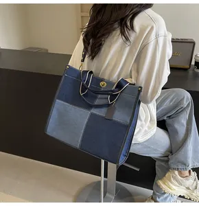 Detail of a large denim tote bag featuring patchwork fabric and a metal twist lock closure