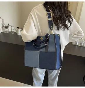 Detail of a patchwork denim tote bag featuring dual handles and adjustable shoulder strap