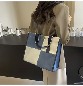 Close-up of a blue and beige canvas tote bag with a golden turn-lock and shoulder strap