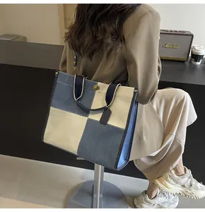 Detail of a color-block patchwork tote bag with denim canvas and a metal twist lock clasp
