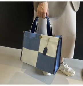 Detail of checkered canvas tote bag with gold twist lock and leather tag held by model