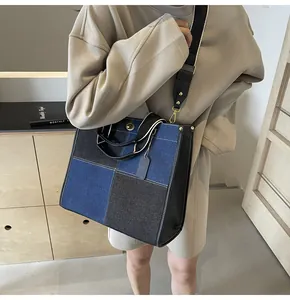 Detail of a large denim tote bag featuring color-block patchwork and wide canvas strap