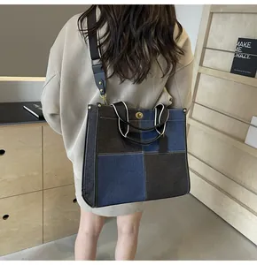 Detail of a color-block denim tote bag featuring metallic turn-lock and leather straps