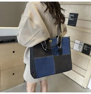 Detail of a large capacity denim tote bag with two-tone splicing and metal twist lock
