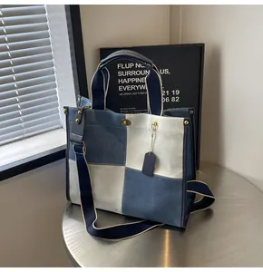 Detail of blue and white canvas tote bag with gold turn-lock closure and shoulder strap