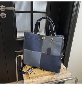Detail of blue denim patchwork tote bag showing golden turn-lock and cylinder handles
