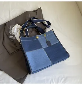 Detail of blue patchwork denim tote bag with metal lock closure and wide shoulder strap
