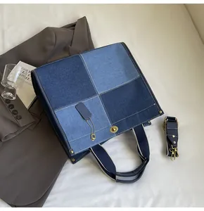 Detail of color-block denim tote bag showing golden twist lock and adjustable strap