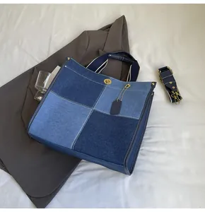 Detailed view of blue denim patchwork tote bag with gold hardware and striped shoulder strap