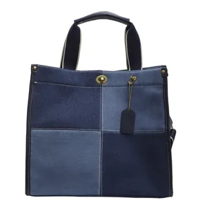 Patchwork denim tote bag with blue color blocks and vintage metal twist-lock closure