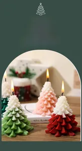 Detailed view of lit Christmas tree shaped scented candles in green and pink hues
