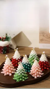 Detailed close-up of gradient Christmas tree candles with golden bells in a wooden tray