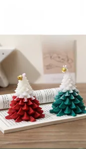 Detail of gradient Christmas tree scented candles with small golden bells on a book