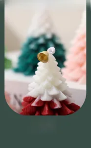 Close-up of red and white gradient Christmas tree candle with golden bell and leaf texture