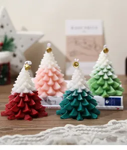 Detail of four gradient Christmas tree candles with small gold bells on a wooden table