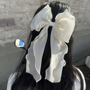 White chiffon bow hair claw clip with long flowing ribbons shown on a ponytail