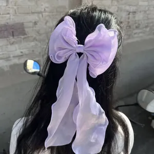 Elegant purple organza bow hair clip with long ribbons on dark hair for women