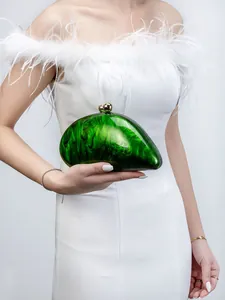 Close-up of green marble acrylic evening clutch with gold spherical metal clasps