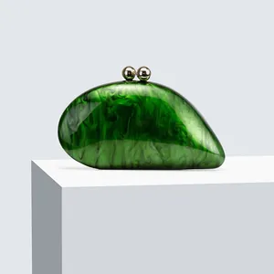 Detailed macro of emerald green marble acrylic clutch featuring polished gold spherical clasp