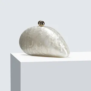 Detailed shot of white marble acrylic clutch featuring elegant gold spherical metal clasp
