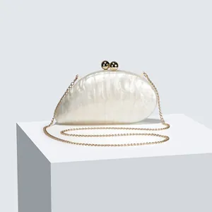 Detailed macro view of acrylic clutch bag with pearl texture and gold chain strap