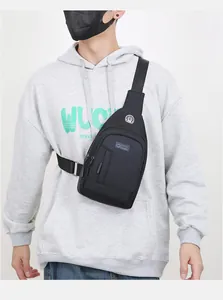 Front view of black oxford fabric sling bag with earphone port on grey sweatshirt