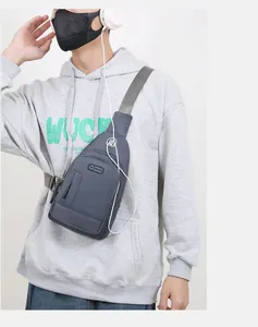 Detail of blue-grey oxford chest bag with earphone port on male model in white studio
