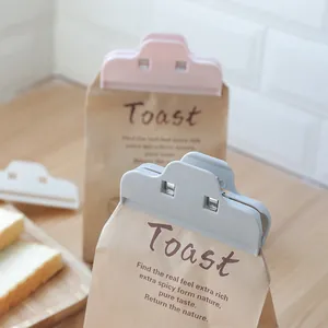 Pink and grey food bag sealer clips for moisture-proof kitchen storage on a wooden surface