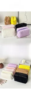 Close-up of plush cosmetic bags in six vibrant colors on a minimalist desk