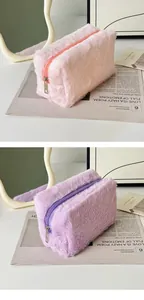 Detailed close-up of soft plush makeup bags in pink and purple with smooth metal zippers