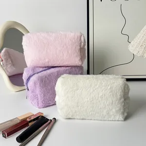 Three plush cosmetic bags in pink, purple, and white with a zipper and furry texture