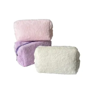 Fluffy plush cosmetic bags in pink purple and white with zippers on white background