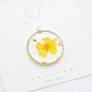 Handmade resin daisy pendant with gold foil leaf in a circular copper frame