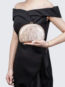 Detail of marble pattern acrylic evening bag with gold clasp held by model in black dress