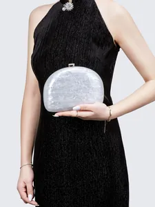 Detail of semi-circular pearl white acrylic clutch bag with marble texture and gold clasp