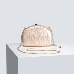 Detailed view of semi-circular acrylic evening bag with pearl texture and gold chain