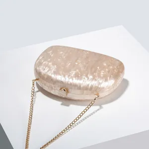 Detail of marble acrylic evening bag with gold metal frame and delicate chain strap