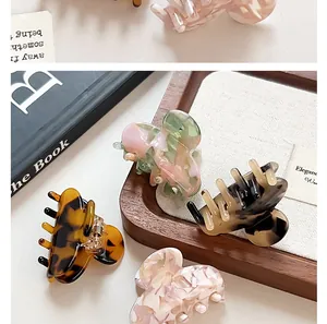 Close-up of elegant acetate hair claws with floral patterns on a wooden tray