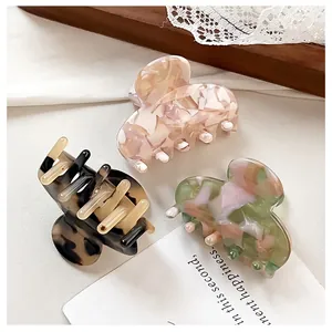 Detailed close-up of three acetate hair claws in tortoise shell and marble patterns