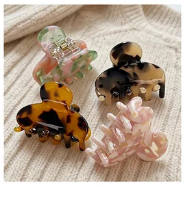 Set of four premium acetate hair claws with marble and tortoiseshell patterns on knit background