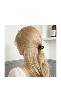 Detail of tortoiseshell resin hair claw clip holding side hair on blonde wavy hair