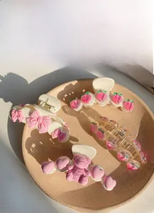 Detailed close-up of large hair claws featuring camellia, pearl, and peach designs