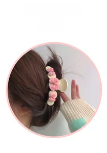 Detail view of a large beige hair claw clip with pink bows worn on a model hair