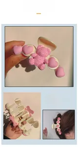 Close-up of a large resin hair claw clip with pink hearts, a smile bear, and metal spring