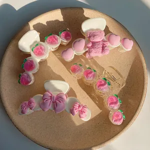 Detailed view of four cute hair claw clips with pink peach and heart motifs on a tray