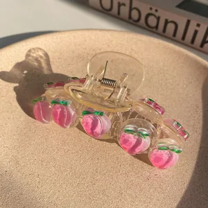 Detail of a large clear hair claw clip with pink peach charms and metal spring